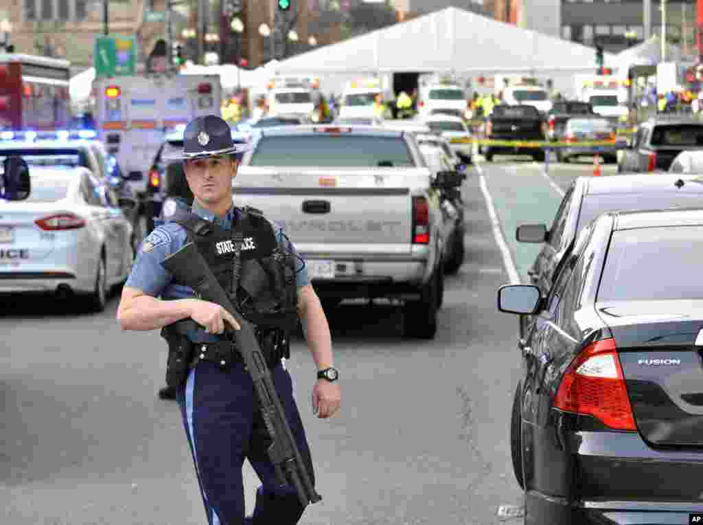 A Massachusetts state police officer guards the area containing the medical tent, rear, following an explosion at the 2013 Boston Marathon, April 15, 2013.