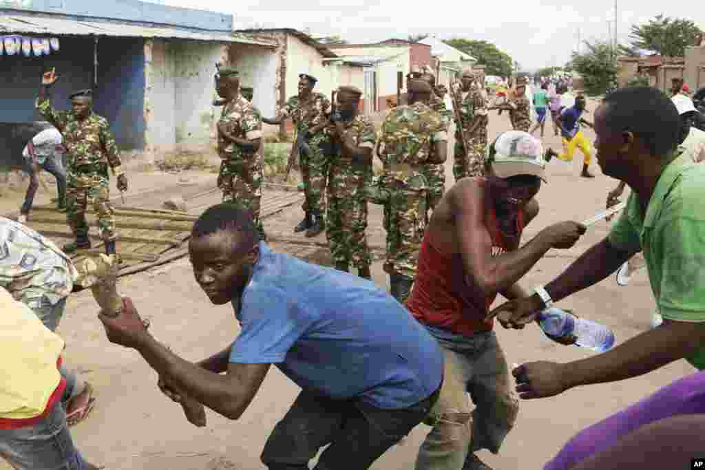 Des soldats tirent en l'air pour disperser des manifestants qui ont acculé Jean Claude Niyonzima un membre présumé de la milice Imbonerakure de la jeunesse du parti au pouvoir dans un égout dans le quartier de Cibitoke de Bujumbura, au Burundi, jeudi 7 mai 2015.
