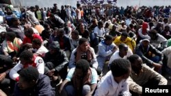 FILE - Illegal African migrants sit during a visit by U.N. officials at a detention camp in Tripoli, Libya, March 22, 2017.