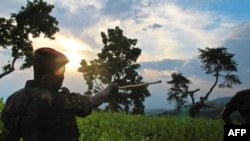 Umusirikare wa M23 yerekana aho bari bigaruriye ku musozi wa Kavumu mu ntara ya Kivu ya Ruguru. Hari taliki 3/6/2012 izo nyeshyamba zitaratsindwa ngo zihungire mu bihugu bituranye na Kongo.