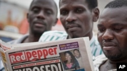 Quelques personnes lisent l'exemplaire d'un journal à Kampala,, 25 février 2014.