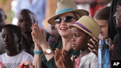 FILE - Madonna claps hands with her daughter Mercy, right, in Kasungu, about 150 kilometers north of the capital Lilongwe, Nov. 30, 2014.
