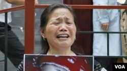 Zheng Shuzhen, seorang nenek di Tiongkok memegang foto cucunya yang meninggal setelah minum susu yang tercemar.