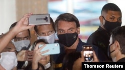 Brazil's President Jair Bolsonaro poses for a picture with supporters amid the COVID-19 outbreak in Brasilia on May 23, 2020.