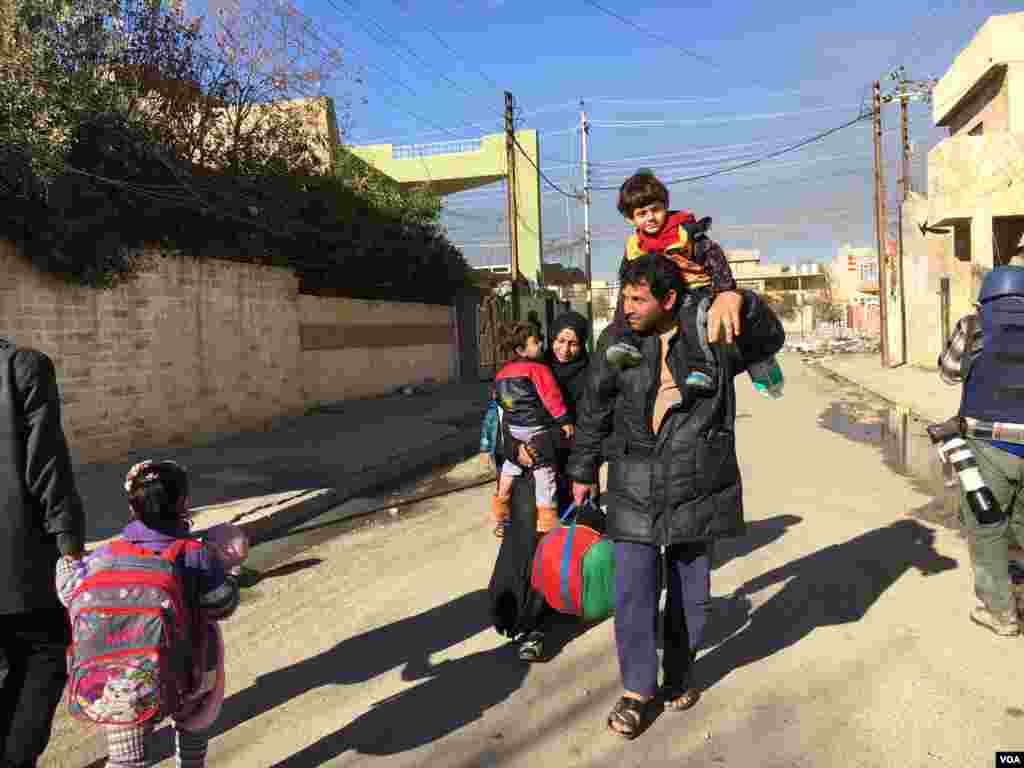 Wani mutum dauke da dansa a kafada da sauran iyalinsa kan hanyar ficewa daga Mosul, Janairu 13, 2017 