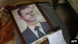 Retrato do Presidente sírio Bashar al-Assad com a moldura partida, nas instalações do Departamento de Segurança Política nos arredores da cidade central de Hama.