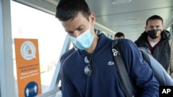 Novak Djokovic looks as his documents after landing in Belgrade, Serbia, Monday, Jan. 17, 2022. Djokovic arrived in the Serbian capital following his deportation from Australia .(AP Photo/Darko Bandic)