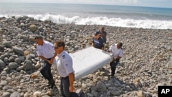 Des policiers français emportent un morceau de débris d'un avion à Saint-André, Ile de la Réunion, le 29 juillet 2015.