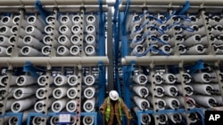 FILE - A worker climbs stairs among some of the 2,000 pressure vessels that will be used to convert seawater into fresh water through reverse osmosis in a desalination plant in Carlsbad, Calif., March 11, 2015. 