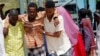 Somalis help a civilian who was wounded in suicide bomb attack at a military base in Mogadishu, Somalia, June, 15, 2021.