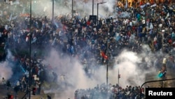 Para penggemar tim Argentina lari dari semprotan gas air mata dalam bentrokan dengan polisi di Buenos Aires, menyusul kekalahan tim itu dari Jerman di Brazil (13/7). (Reuters/Ivan Alvarado)