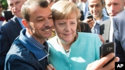 FILE - German chancellor Angela Merkel poses for a selfie with a refugee in a facility for arriving refugees in Berlin, Sept. 9, 2015. 