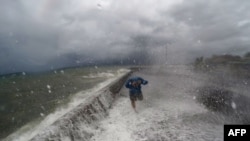 A resident walks past waves spilling over a wall onto a coastal road in the city of Legaspi in Albay province, south of Manila on December 14, 2015, as typhoon Melor approaches the city. 