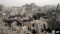 This citizen journalism image from the Aleppo Media Center (AMC) shows people searching debris of destroyed buildings after Syrian government forces airstrike, Jabal Bedro, Aleppo, Feb. 19, 2013.