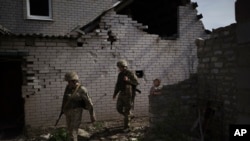 Tentara pemerintah Ukraina berjalan di area perumahan yang hancur di dekat garis perbatasan antara negara tersebut dan wilayah yang dikuasai kelompok separatis di Donetsk pada 4 Mei 2021. (Foto: AP/Felipe Dana)
