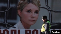 An Interior Ministry officer walks past a board displaying a portrait of jailed former Ukrainian Prime Minister and opposition leader Yulia Tymoshenko at a protest tent camp set up by her supporters in central Kyiv, Nov. 18, 2013.