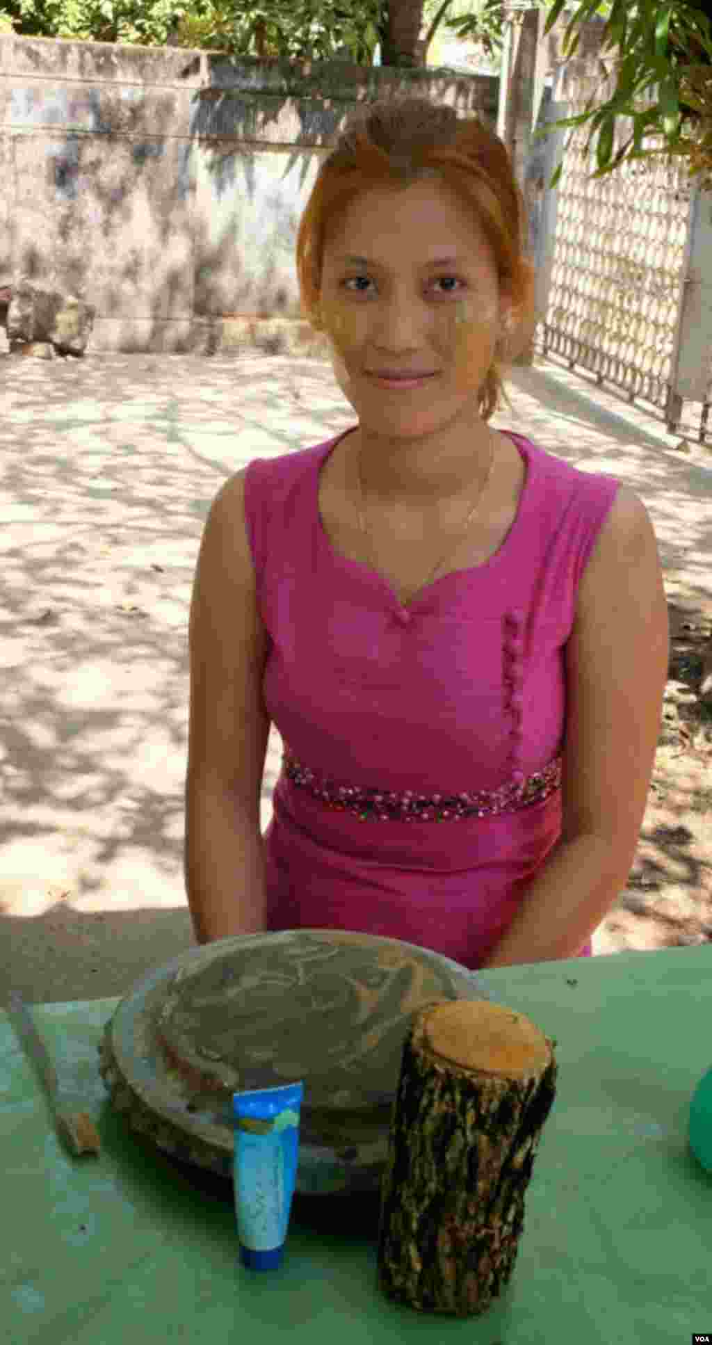 Seorang perempuan memperlihatkan pipinya yang berulas bedak dingin thanaka. (VOA/Steve Herman)