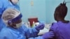 A woman is injected by a health care worker, left, as she takes part in an Ebola virus vaccine trial, at one of the largest hospital's Redemption hospital in Monrovia, Liberia, Monday, Feb. 2, 2015. A large-scale human trial of two potential Ebola vaccine