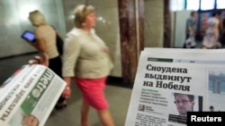 An employee distributes newspapers, with a photograph (R) of former U.S. spy agency contractor Edward Snowden seen on a page, at an underground walkway in central Moscow, Russia, July 2, 2013.