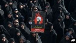 Seorang perempuan Iran di Teheran, Iran, mengacungkan poster Sheikh Nimr al-Nimr, seorang ulama Syiah terkenal yang dieksekusi oleh Arab Saudi, 4 Januari 2016.
