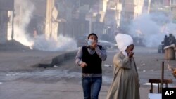 Egyptians react to tear gas fired by security forces to disperse a protest by supporters of ousted President Mohammed Morsi demanding his reinstatement, in Cairo, Egypt, Dec. 6, 2013. 
