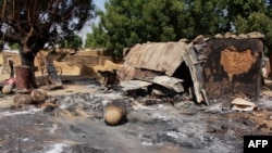 Des cases incendiées par des combattants de Boko Haram dans le village de Maiborti, dans la banlieue de Maiduguri, dans le nord-est du Nigeria, le 17 décembre 2018 (Photo AUDU MARTE / AFP)