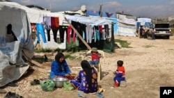 FILE - Syrian women prepare food for their family outside their tents, at a Syrian refugee camp in the town of Bar Elias, in Lebanon's Bekaa Valley, March 29, 2016. 