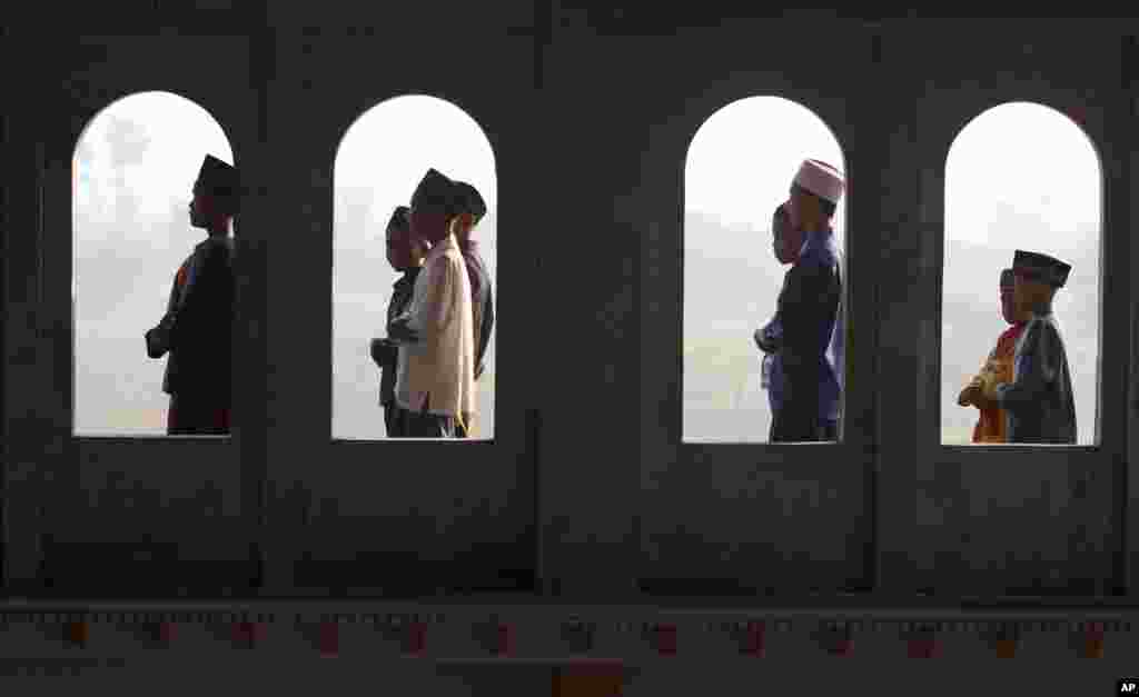Muslim youths are seen through the windows of a mosque as they perform Eid al-Fitr morning prayers, Porong, East Java, Indonesia, August 8, 2013.
