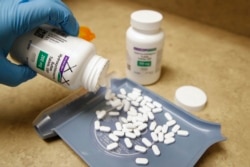 FILE - A pharmacy tech pours out pills of hydroxychloroquine at Rock Canyon Pharmacy in Provo, Utah, May 20, 2020.
