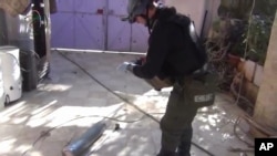 Imagen tomada de un video aficionado en la que aparece un supuesto investigador de la ONU examinando un cartucho en Moadamiyeh, en las afueras de Damasco.