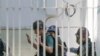 Wartawan Jepang Yuki Kitazumi mengangkat tangannya saat dia dikawal oleh polisi setibanya di kantor polisi Myaynigone di kota Sanchaung di Yangon, Myanmar. (Foto: AP)