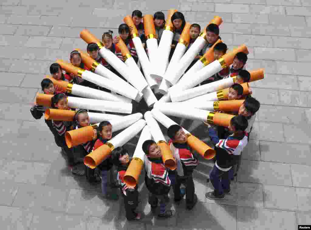 Para siswa sebuah sekolah dasar di Handan, Provinsi Hebei, Cina berpose dengan "model rokok besar" dalam kampanye menjelang Hari Tanpa Tembakau Sedunia, 29 Mei 2013.