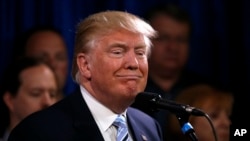 Republican presidential candidate Donald Trump smiles as he stands with 22 delegates from North Dakota to the Republican National Convention in Bismarck, N.D., May 26, 2016.