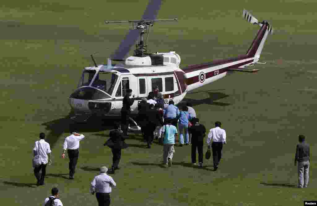 Police officers escort election commission officials to a helicopter at the Thai-Japan youth stadium in central Bangkok, Dec. 26, 2013.