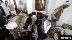FILE - People help an injured man at the scene of a suicide bombing inside a mosque in Sana'a, Yemen, March 20, 2015.