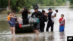 Warga berjalan melewati jalanan yang banjir setelah dievakuasi dari rumah mereka yang diterjang banjir di Houston (Foto: dok). Lima tentara tewas dan empat lainnya masih hilang setelah kendaraan mereka terbalik di anak sungai yang banjir di pangkalan angkatan darat AS di Texas, Fort Hood, Kamis (2/6).