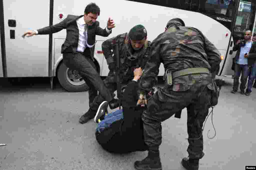A protester is kicked by Yusuf Yerkel (L), advisor to Turkey's Prime Minister Tayyip Erdogan, as Special Forces police officers detain him during a protest against Erdogan's visit to Soma, a district in the country's western province of Manisa, May 14, 2014.