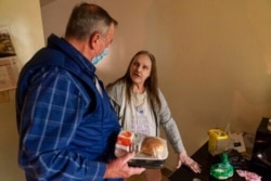 Meals on Wheels of Rhode Island driver Jim Stotler, left, delivers a meal to Rhonda Valoir, 66, at her apartment in Pawtucket, Nov. 20, 2020.