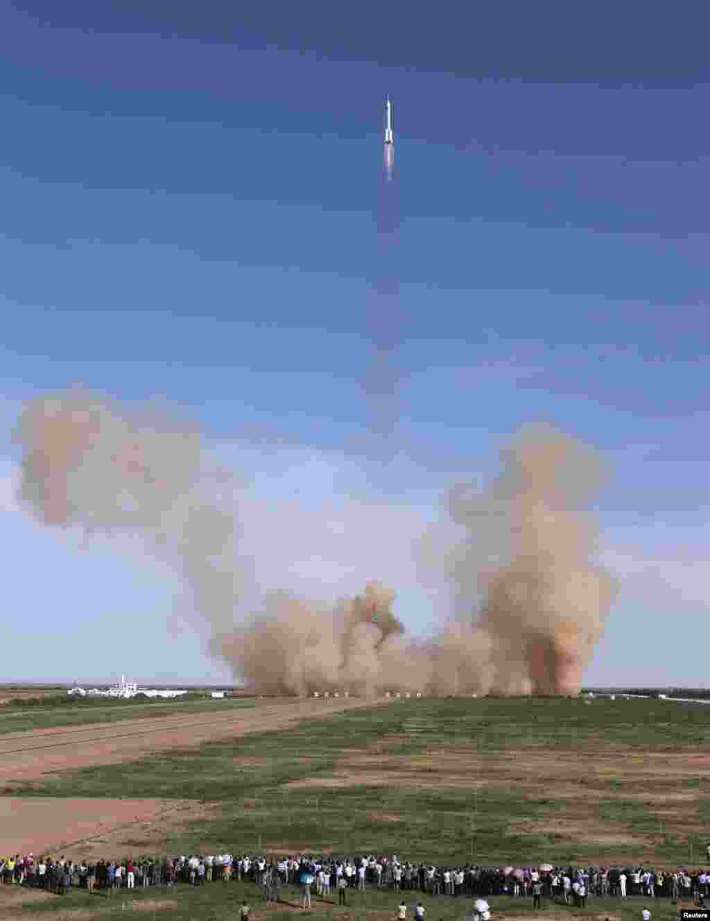 People watch as the Long March 2-F rocket loaded with the Shenzhou-10 manned spacecraft lifts off, Gansu province, China, June 11, 2013.