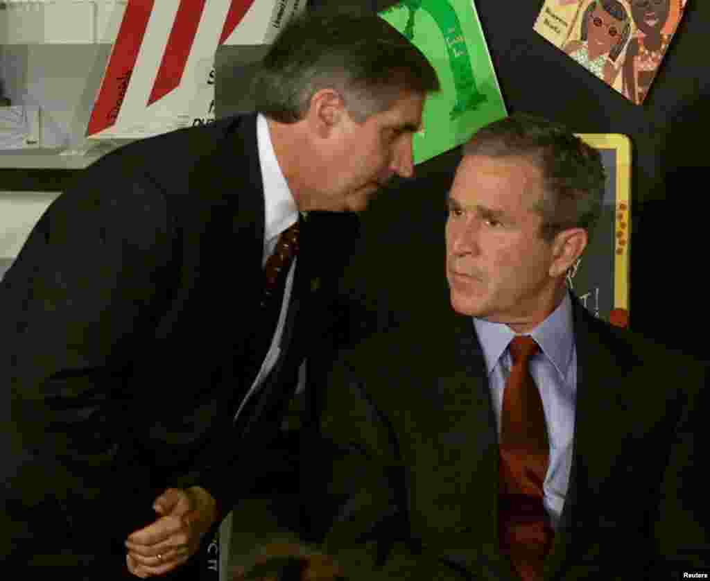 Le président George W Bush écoute le chef de la Maison-Blanche lui annoncer qu'un deuxième avion a percuté la seconde tour du World Trade Center alors que le président se trouve devant une classe dans une école primaire en Floride, le 11 septembre 2001.
