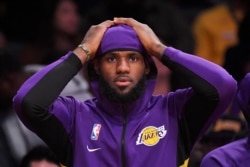 FILE - Los Angeles Lakers forward LeBron James sits on the bench during the first half of a preseason NBA basketball game against the Golden State Warriors, Oct. 14, 2019, in Los Angeles.