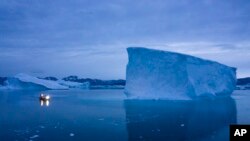 Sebuah kapal yang berlayar pada malam hari, bergerak melewati bongkahan es besar di wilayah timur Greenland pada 15 Agustus 2019. (Foto: AP/Felipe Dana)