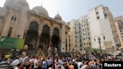 Pemrotes anti-Morsi dan polisi anti huru-hara berkumpul di luar masjid al-Fatah di Lapangan Ramses, Kairo (17/8).