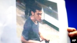 Seorang polisi perempuan Malaysia memegang foto warga Iran berusia 19 tahun yang diidentifikasi sebagai Pouria Nour Muhammad Mehrdad, sedang memasuki pesawat Malaysia Airlines dengan nomor penerbangan MH370 dengan paspor curian (11/3).