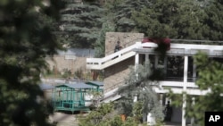 An Afghan policeman runs during a gun battle with militants outside of the Spozhmai Hotel on Lake Qurgha, where security officials say Taliban insurgents killed nearly two dozen people in an attack just north of Kabul, June 22, 2012. 