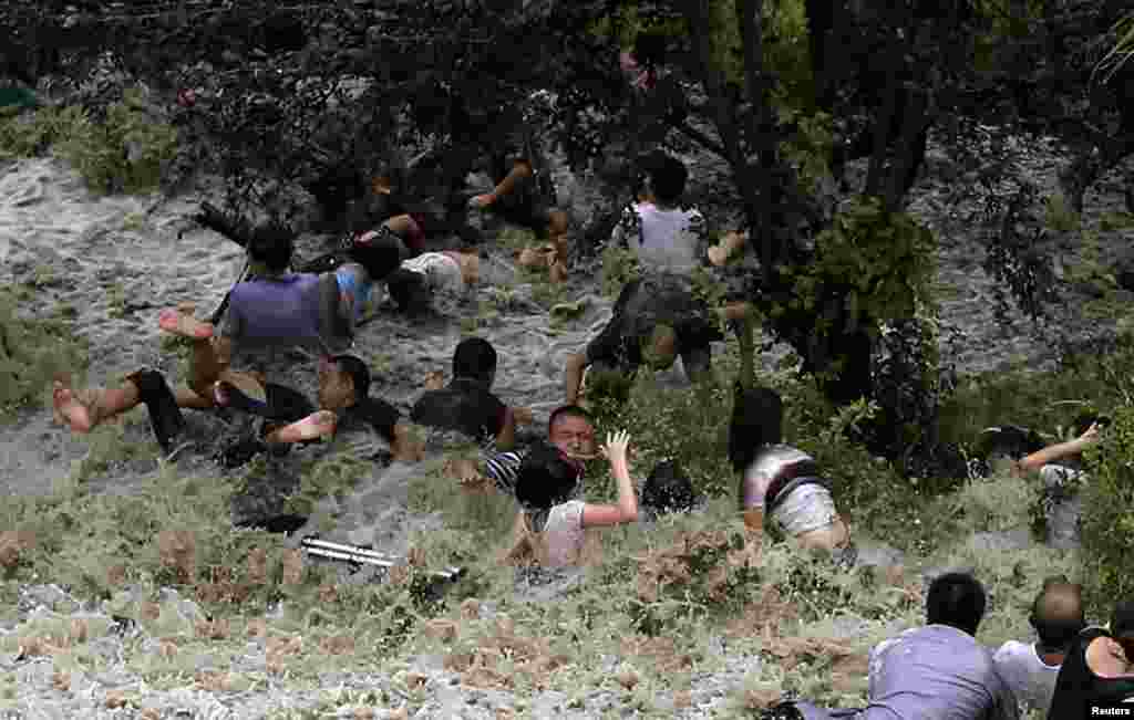 Orang-orang berjuang melawan gelombang pasang yang menabrak penghalang di tepi sungai Qiantang di Provinsi Haining, Zhejiang, akibat serangan topan Trami di Cina Timur.