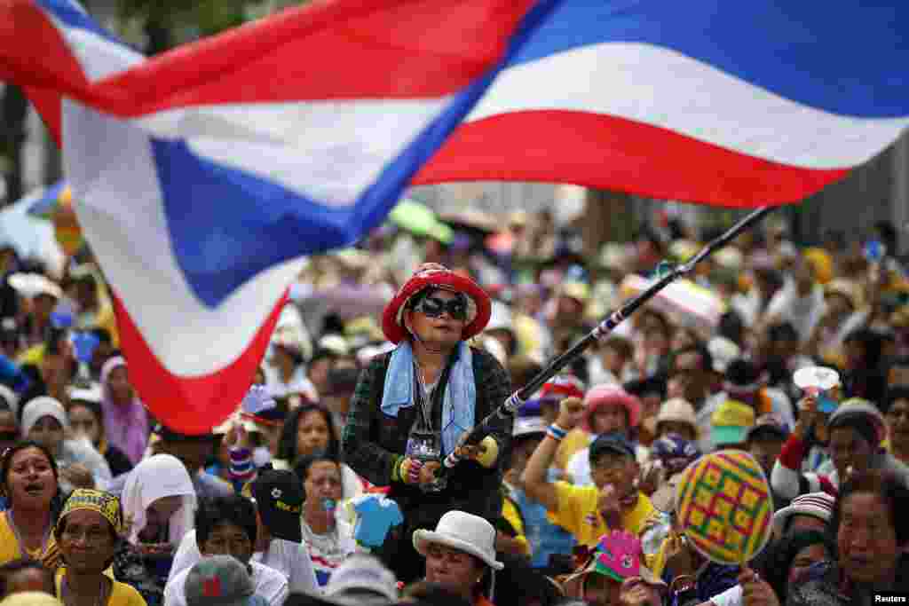 Seorang pengunjuk rasa anti-pemerintah melambaikan bendera dalam sebuah unjuk rasa di luar kompleks parlemen negara itu di mana anggota Senat berkumpul untuk sebuah pertemuan, di Bangkok, Thailand. 