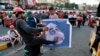Protesters hit a poster showing Iraqi Prime Minister Adel Abdel-Mahdi with shoes during ongoing anti-government protests in Baghdad, Iraq, Nov. 3, 2019. 