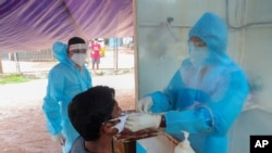 A health worker takes a nasal swab sample to test for COVID-19 in Hyderabad, India, Sunday, Sept. 13, 2020. India's coronavirus cases are now the second-highest in the world and only behind the United States. (AP Photo/Mahesh Kumar A.)