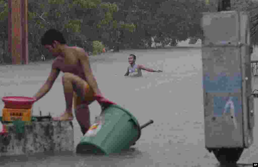 A man wades in chest-deep floods as another retrieves his belongings in Quezon City, Philippines, August 7, 2012.